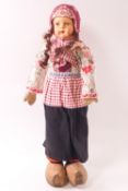 An early 20th century Dutch costume doll with papier-mâché face and wooden clogs,