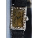 A white metal cocktail watch with black ribbon strap.