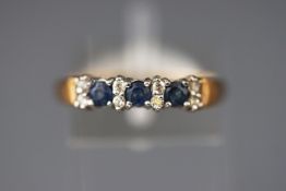 A yellow metal half hoop ring set with three sapphires and inter spaced with ....