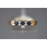 A yellow metal half hoop ring set with three sapphires and inter spaced with ....
