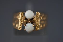 A yellow metal two stone ring set with round cabochon cut commercial opals.