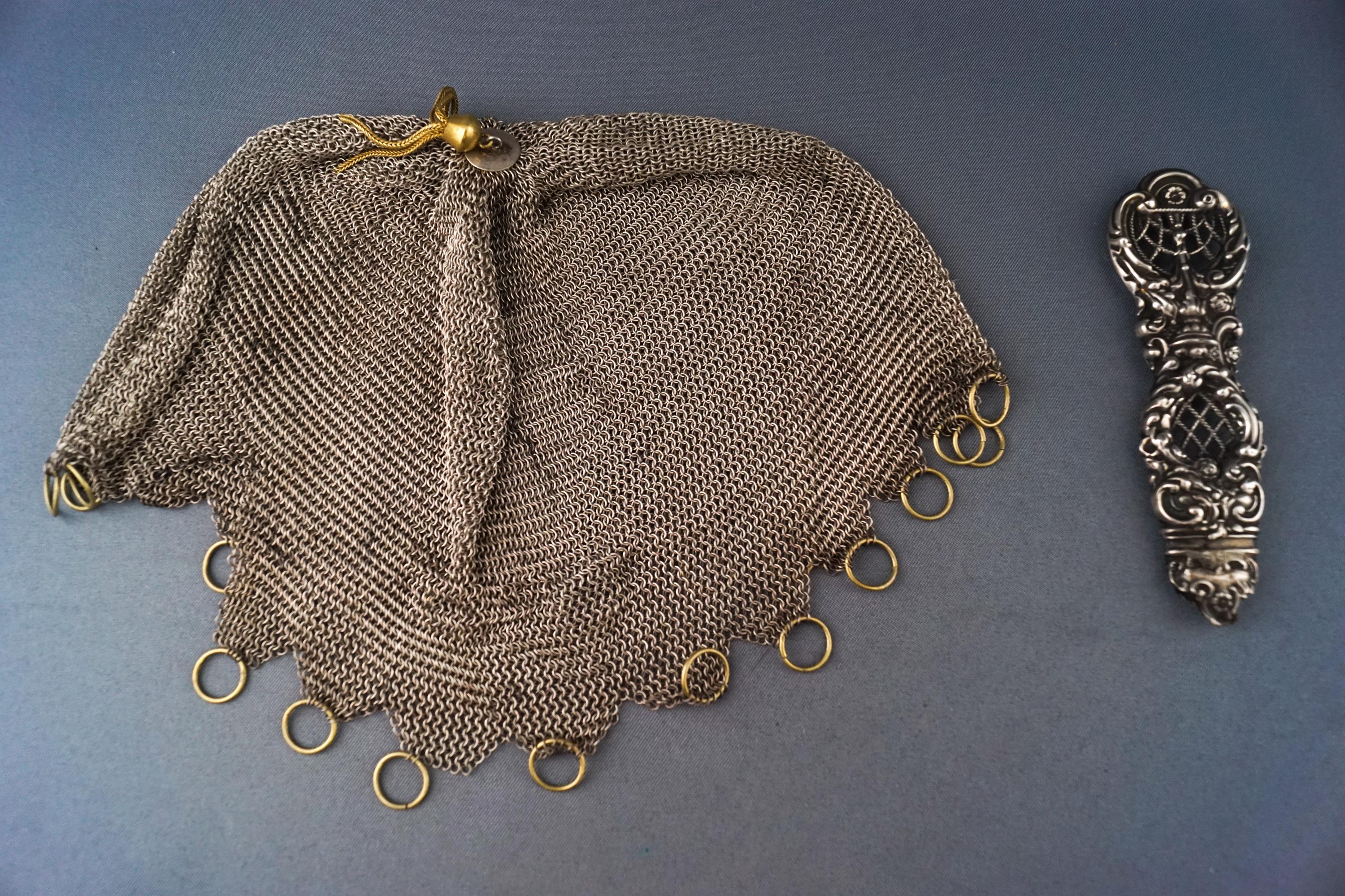 A white metal chain link draw string purse and a decorative handle