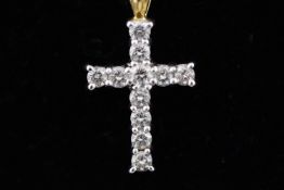 A yellow and white metal cross pendant set with eleven round brilliant cut diamonds.