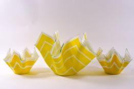 Three glass handkerchief bowls decorated with white stripes on yellow ground,