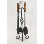 A wrought iron fire companion set, the stand holding four fire irons on four scroll feet,