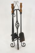 A wrought iron fire companion set, the stand holding four fire irons on four scroll feet,