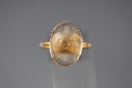 A yellow metal single stone ring set with an oval cabochon cut rutilated quartz