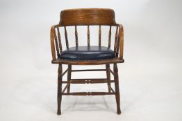 An oak tub desk chair, with curved back rail and arms, raised on bobbin turned spindles,