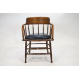 An oak tub desk chair, with curved back rail and arms, raised on bobbin turned spindles,