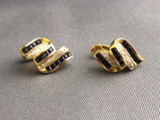 A yellow metal pair of stud earrings each set with square cut sapphires