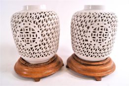 A pair of Blanc de Chine decorated pierced vases on wooden stands,