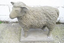A reconstituted stone figure of a sheep on plinth base, 61cm high, 66cm wide,