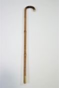 A walking stick with gold band and snakeskin and ivory handle,