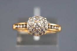 A yellow metal diamond set cluster ring with diamond shoulders.