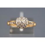 A yellow metal diamond set cluster ring with diamond shoulders.