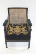 A Regency style black finished wood bergere armchair with curved back rail and padded arms
