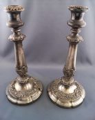 A pair of Sheffield plate candlesticks with decorated sconces over a foliate decorated baluster stem