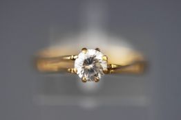 A yellow metal single stone ring set with a round faceted cut cubic zirconia.