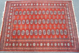 A Caucasian style rug with three rows of thirteen medallions on a red ground within multiple