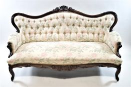 A Victorian carved mahogany Rococo style sofa with shaped and carved cresting rail over a deep