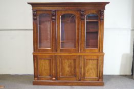 A Victorian mahogany breakfront bookcase with flared plinth above three glazed doors