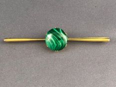 A yellow metal bar brooch centrally set with a circular cabochon malachite (untested) Pin