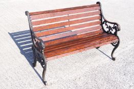 A teak slat garden bench with cast iron ends of fancy C & S scroll form