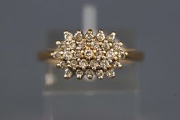 A yellow and white metal cluster ring set with round brilliant cut diamonds.