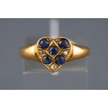 A yellow metal ring stylized as a heart and set with five round cut sapphires