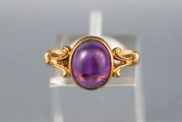 A yellow metal single stone ring. Set with an oval cabochon cut amethyst.
