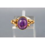 A yellow metal single stone ring. Set with an oval cabochon cut amethyst.