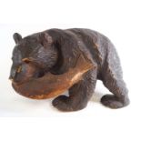 A carved black forest style figure of a bear holding a salmon in his mouth,