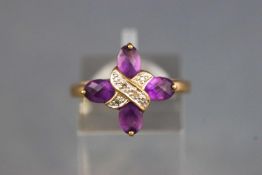 A yellow metal dress ring set with four faceted cut amethyst