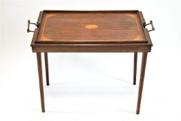 An Edwardian mahogany two handled tray/table with central satinwood patera on square tapering legs,