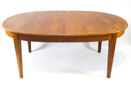 A 1970s teak extending dining table with D ends and two loose leaves on square tapering legs,