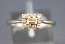 A white metal cluster ring set with a central baguette cut diamond