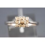 A white metal cluster ring set with a central baguette cut diamond