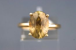 A yellow metal single stone ring. Set with a fancy faceted cut yellowish green chrysoberyl.