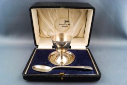 A cased silver egg cup and spoon, the cup with decorated edge on a shaped base by Walker & Hall,