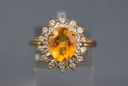 A yellow and white metal cluster ring. Set with an oval faceted cut citrine.