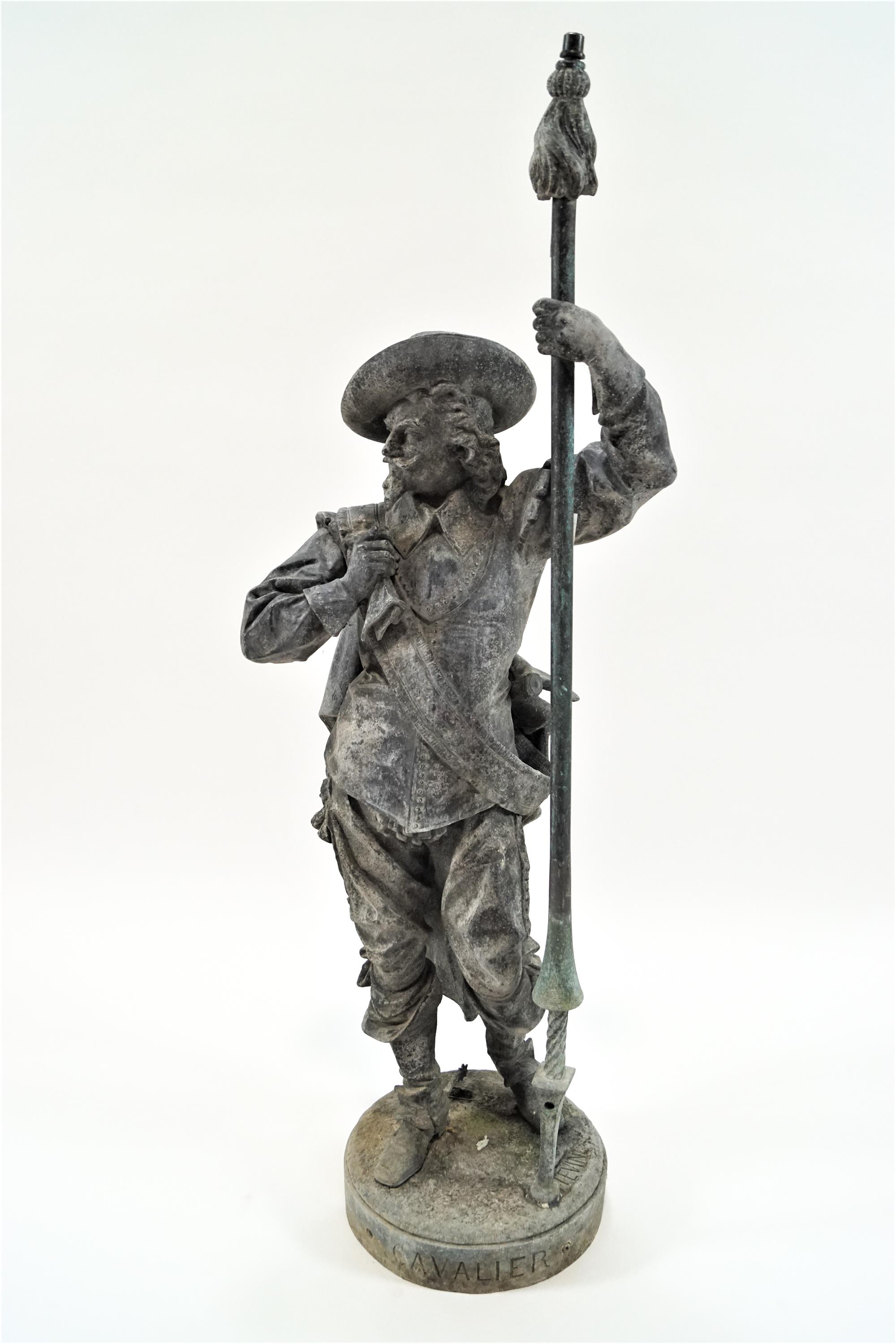 A cast metal statue of a man in Van Dyck style costume with a hat and georgette plate,