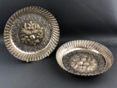 A pair of silver sweet meat dishes with fluted edges and centres heavily decorated with repousse