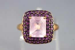 A yellow metal cluster ring set with a cushion cut pale amethyst