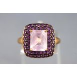 A yellow metal cluster ring set with a cushion cut pale amethyst