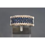 A white metal half hoop dress ring set with three rows of blue sapphires
