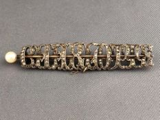 A yellow and white metal bar brooch spelling 'Charlotte' and set with rose cut diamonds.