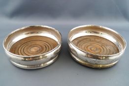 A pair of silver decanter coasters of plain bellied form with turned wooden bases, London, 1928,