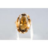 A yellow metal single stone ring set with a large oval faceted cut smokey quartz.