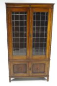 An oak display cabinet with two lead glazed doors, above two panelled doors on square feet,