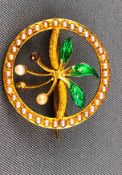 A yellow metal brooch of abstract design set with seed pearls and finished with green enamel.